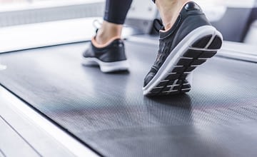 cropped shot of woman in jogging sneakers running on treadmill