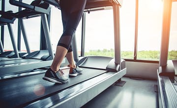 Close up of people who exercising on treadmill. Close-up of woman legs walking by treadmill in sports club. Fitness and Body build up concept. Workout and Strength training concept. Sport club theme.