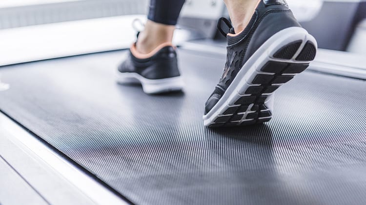 cropped shot of woman in jogging sneakers running on treadmill