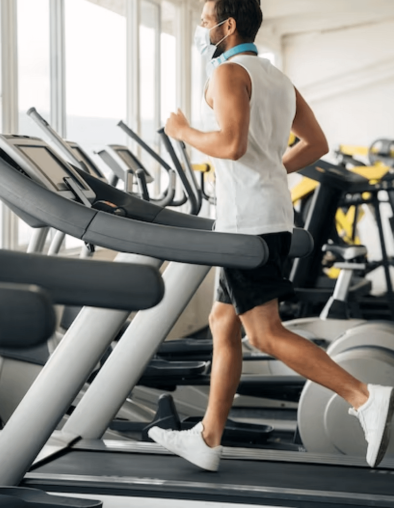 man running on a treadmill wearing a mask