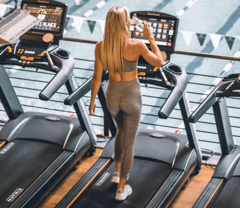 Girl walking on treadmill drinking water